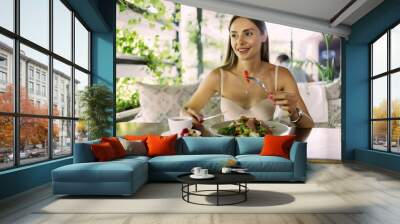 Young woman eating healthy food sitting in the beautiful interior Wall mural